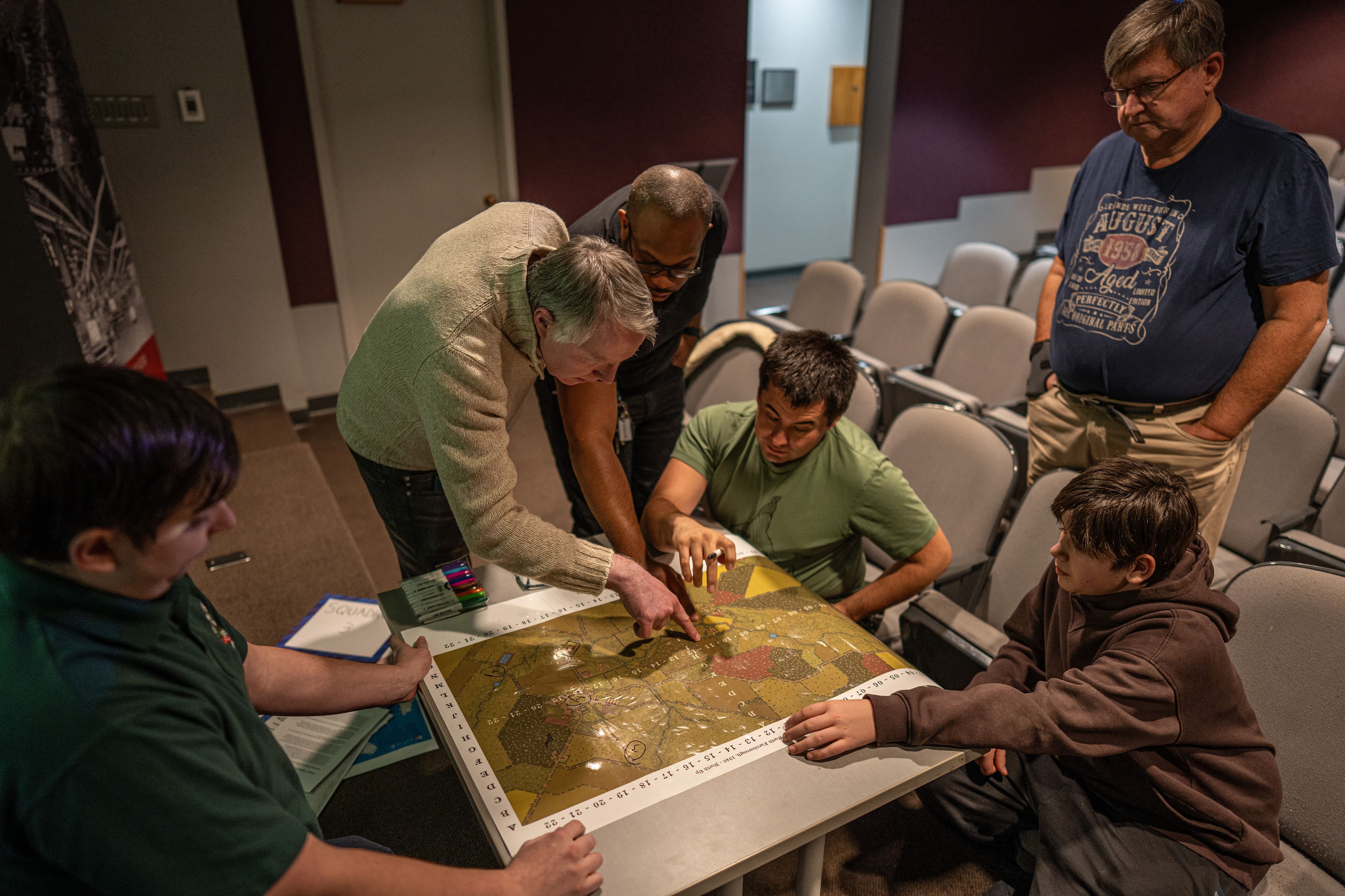 Participants gathered around a tabletop map during a wargaming session.