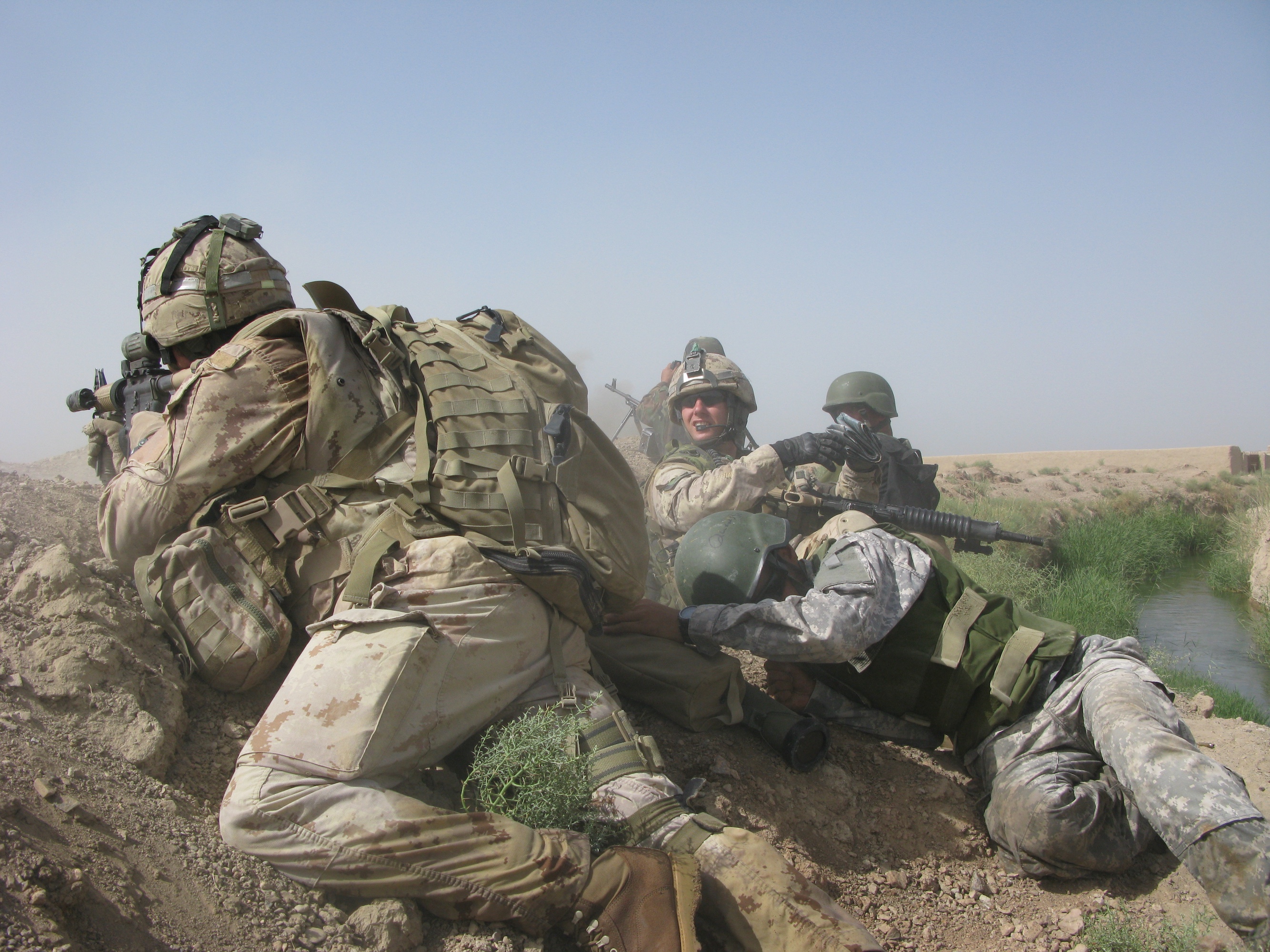 Canadian soldiers taking cover on a dirt berm during a firefight in Afghanistan.